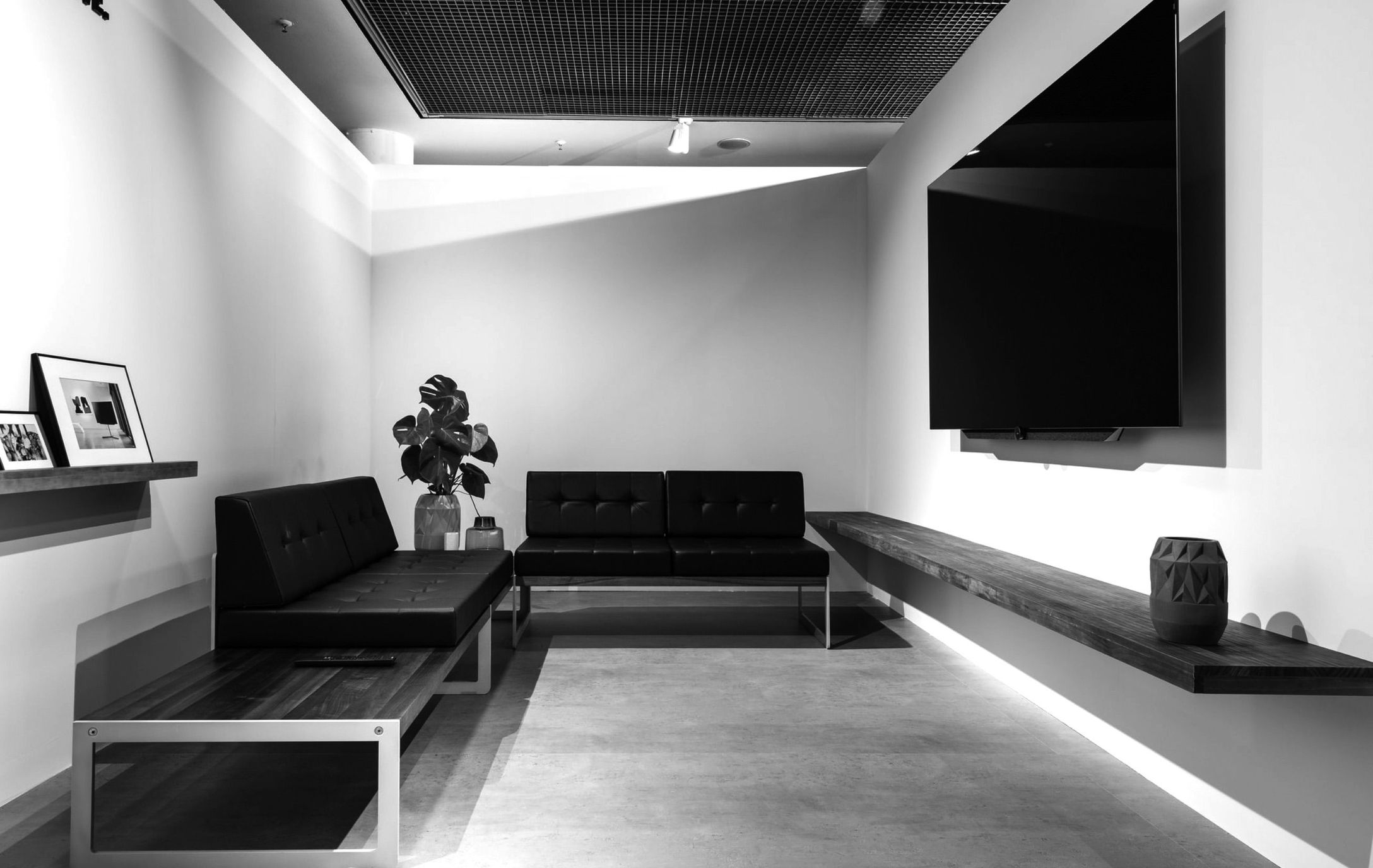 Ein Raum mit zwei Sofas und einem Fernseher. Schwarz-weiß