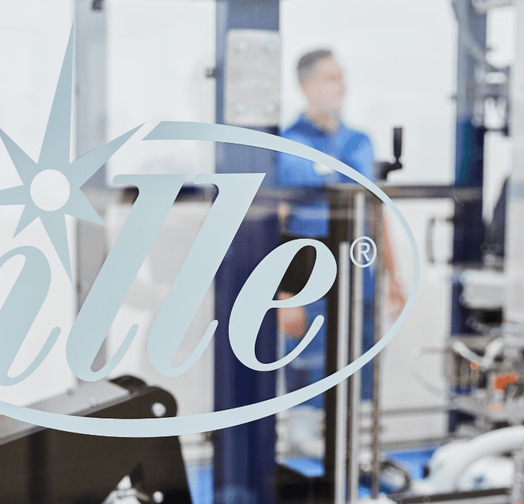 Ille Logo auf Glasscheibe, Mitarbeiter im Hintergrund